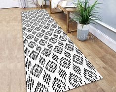 a white and black area rug on the floor next to a potted green plant