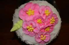 a cake with white frosting and pink flowers on it's icing surface