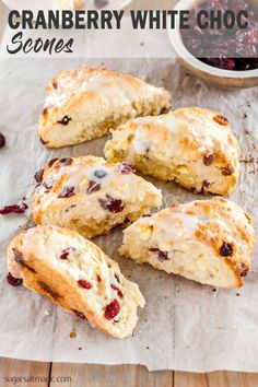 cranberry scones on parchment paper next to bowl of fruit