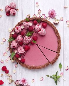 a pie with raspberries and other toppings on it sitting on a table