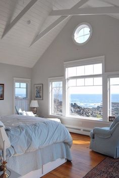 a bedroom with a large bed and two windows overlooking the ocean is pictured in this image