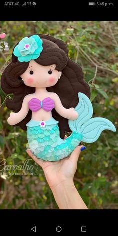 a hand holding up a doll with a mermaid tail