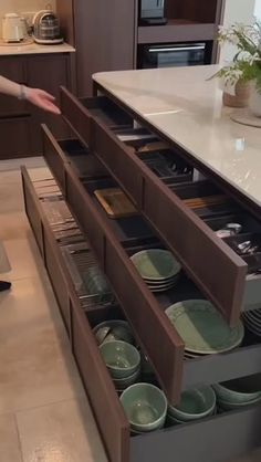 a person reaching for plates in a kitchen drawer