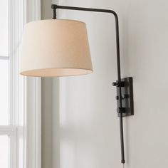 a lamp that is on the side of a wall next to a window with white curtains