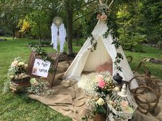 a teepee is set up in the grass with flowers and other items around it