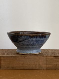 a blue and white bowl sitting on top of a wooden table next to a wall