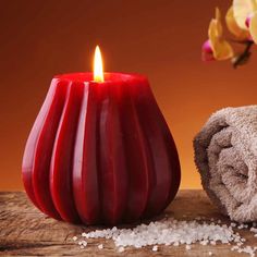 a red candle sitting next to a pile of sea salt on top of a wooden table