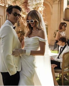 a man and woman standing next to each other in front of a wedding ceremony venue