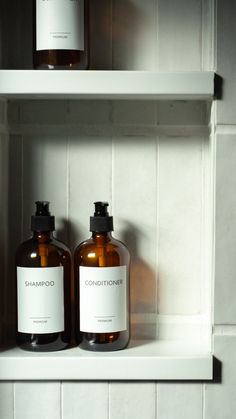 two bottles of shampoo sitting next to each other on a shelf in a bathroom