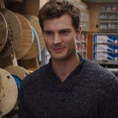 a man is standing in front of some wooden barrels and looking at the camera with a smile on his face