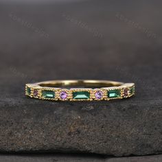 a gold band with green and pink stones