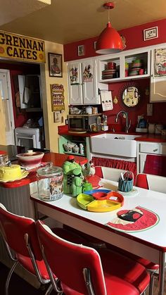 a kitchen filled with lots of red chairs next to a white table topped with plates and bowls