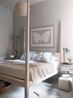 a bedroom with a four poster bed, white walls and flooring is pictured in this image