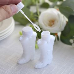 someone is holding a toothbrush in front of two small white plastic bottles on a table