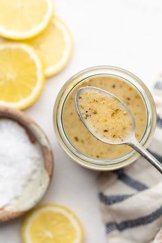 a glass jar filled with lemon curd next to sliced lemons and powdered sugar