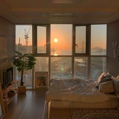 the sun is setting in an apartment with large windows and a view of the water