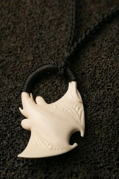 a white necklace with an animal head on it's back end hanging from a black cord