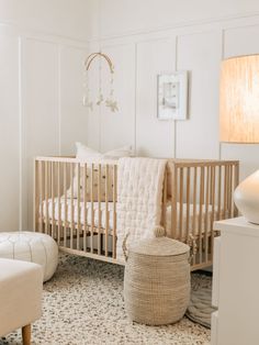 a baby's room with a crib, chair and ottoman in the corner