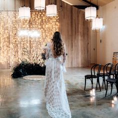 a woman in a white dress is walking through a room with lights on the walls