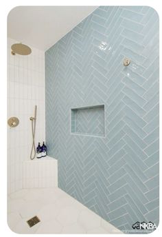 a bathroom with blue and white tile on the walls, shower head, and toilet