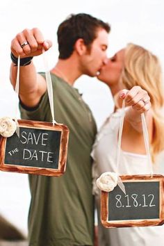 a man and woman kissing in front of a chalkboard sign that says save the date