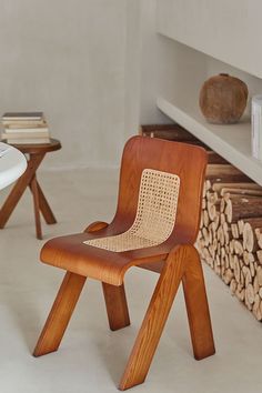 a wooden chair sitting next to a stack of books on top of a white table