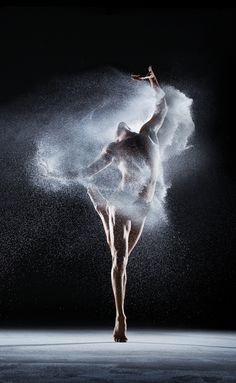 a ballerina is dancing in the dark with white powder on her body and arms