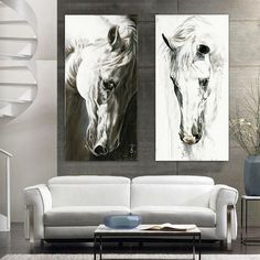 two paintings of horses are hanging on the wall in a living room with white furniture