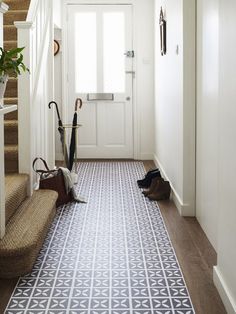 a hallway with an umbrella and some shoes on the ground next to it, in front of a white door