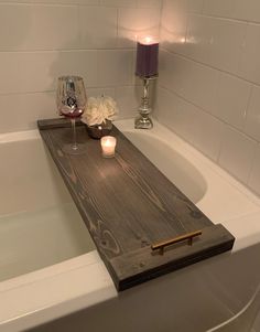 a candle is sitting on top of a wooden tray in the bathtub with candles