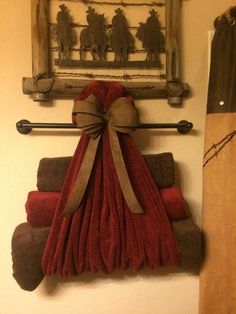 towels are stacked on top of each other in front of a towel rack with a bow