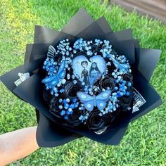 a bouquet made out of black paper with blue flowers and pictures on the center is held in someone's hand