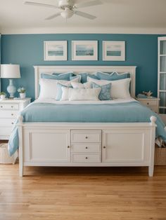 a bedroom with blue walls, white furniture and pictures on the wall above the bed