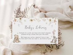 a baby shower sign sitting on top of a white sheet with flowers and leaves around it