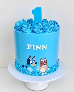 a blue cake with cartoon characters on it and the number one frosted in fondant