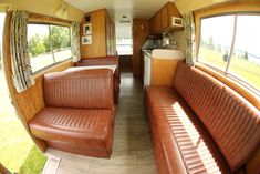 the inside of an rv with leather couches and windows on either side of it