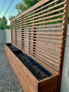 a wooden planter filled with gravel next to a fence