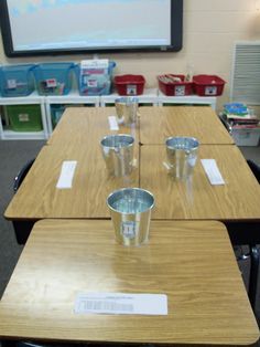 three tables with cups on them in front of a projector screen