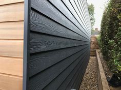 the side of a house that is made out of wood and has black siding on it