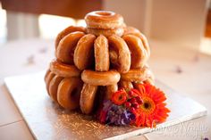 a stack of doughnuts sitting on top of a silver tray next to an orange flower