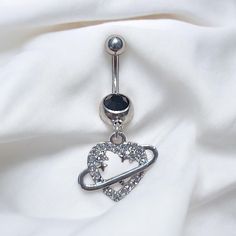 a silver belly ring with an arrow and stars on it, sitting on a white cloth