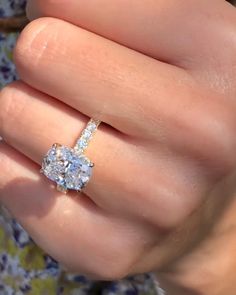 a woman's hand with a diamond ring on top of her finger and the other hand holding an engagement ring