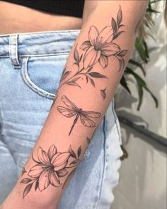 a woman's arm with flowers and a dragonfly tattoo on her left arm