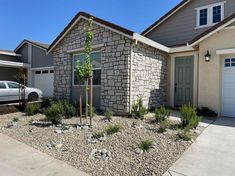 a car parked in front of a house with rocks and gravel around the driveway area