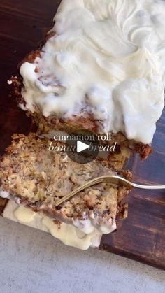 a piece of cake with white frosting sitting on top of a wooden cutting board