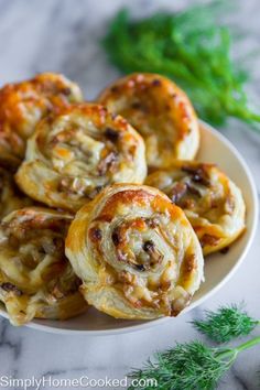 some very tasty looking pastries on a white plate with green sprigs