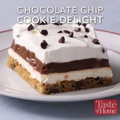 a piece of cake on a plate with chocolate chips and cream toppings, ready to be eaten