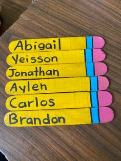 four matchesticks with names on them sitting on top of a wooden table in front of a person's hand