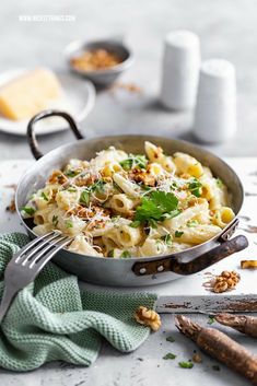 a pan filled with pasta and garnished with parmesan cheese on top