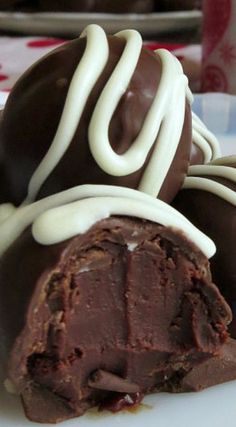 two chocolate covered desserts on a plate with white icing and drizzle